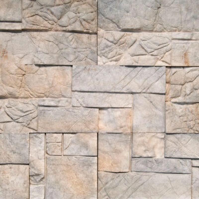 Panel rectangular de aplacado con textura de piedra natural en tonos grises y beige, acabado rústico con relieve y variaciones de color que imitan la piedra cantera.