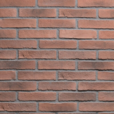 Superficie de ladrillo cerámico visto con textura rústica en tonos terracota y marrones cálidos, dispuesto en patrón de soga con juntas grises visibles y acabado mate natural.