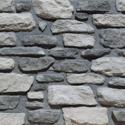 Aplacado de hormigón en tonos grises con textura irregular de piedra natural. Piezas rectangulares de diferentes tamaños dispuestas en patrón horizontal, superficie rugosa y acabado mate con variaciones de color ceniza y gris oscuro.