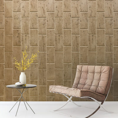 Espacio contemporáneo con pared de piedra travertino olivillo oscuro en formato rectangular, combinado con mobiliario moderno en tonos beige y blanco, complementado por mesa auxiliar y florero con flores amarillas.