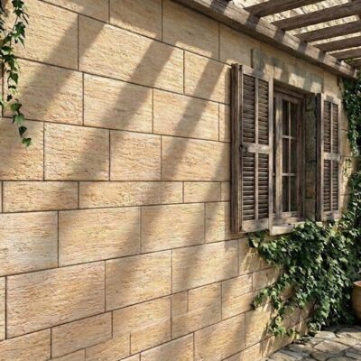 Pared exterior revestida con aplacado efecto piedra Palatino beige en tonos cálidos, con pergolado de madera en la parte superior, plantas trepadoras y macetas de terracota a los pies.