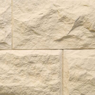 Aplacado de hormigón con efecto piedra natural en tonos crema y beige, formato rectangular con superficie texturizada y acabado rústico irregular, mostrando variaciones de color y relieve característico.