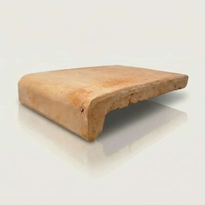Pieza de barro natural con forma de peldaño y perfil redondeado, tonalidad tierra cálida con textura rústica y acabado mate. Superficie con pequeñas irregularidades características del material artesanal.