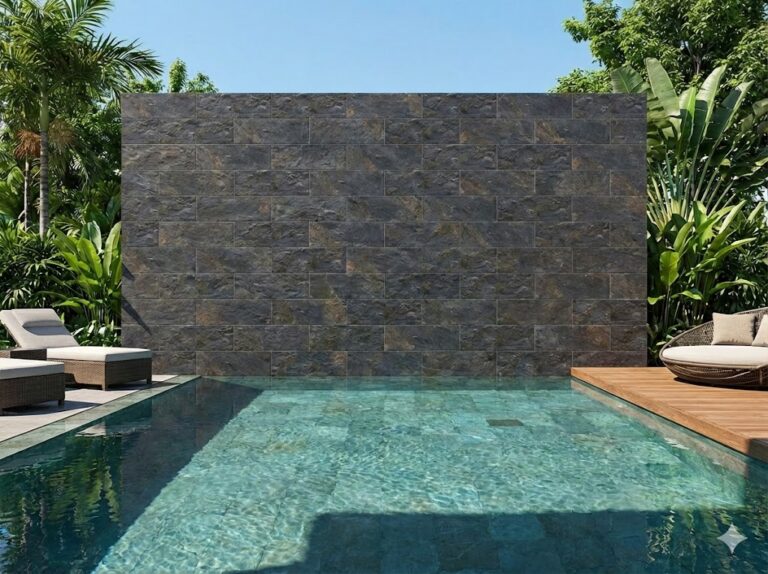 Área de piscina con revestimiento de pared en plaquetas imitación piedra grafito, rodeada de vegetación tropical y zonas de descanso con madera y textiles.