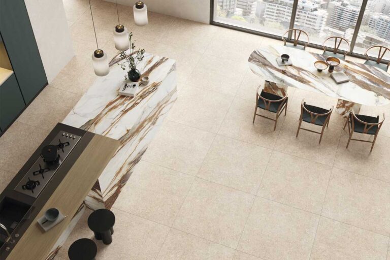 Comedor de lujo con suelo de gres porcelánico efecto piedra en tonos beige y grises, mobiliario de madera clara, lámparas colgantes minimalistas y grandes ventanales con vistas urbanas.