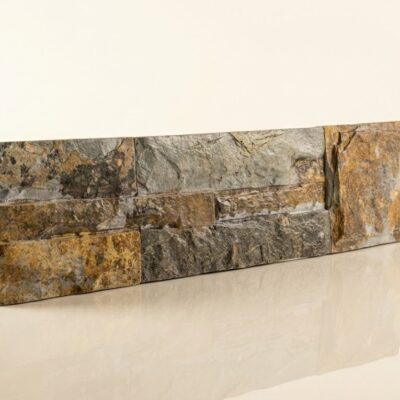 Aplacado de pared con piezas irregulares en tonos grises y ocres, imitando piedra natural pizarra. Superficie texturizada y mate con acabado rústico.