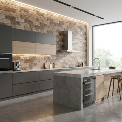 Cocina contemporánea con revestimiento de pared efecto piedra en tonos beige y marrón, isla central de hormigón con barra de bar, muebles grises y ventanal con vistas al exterior.