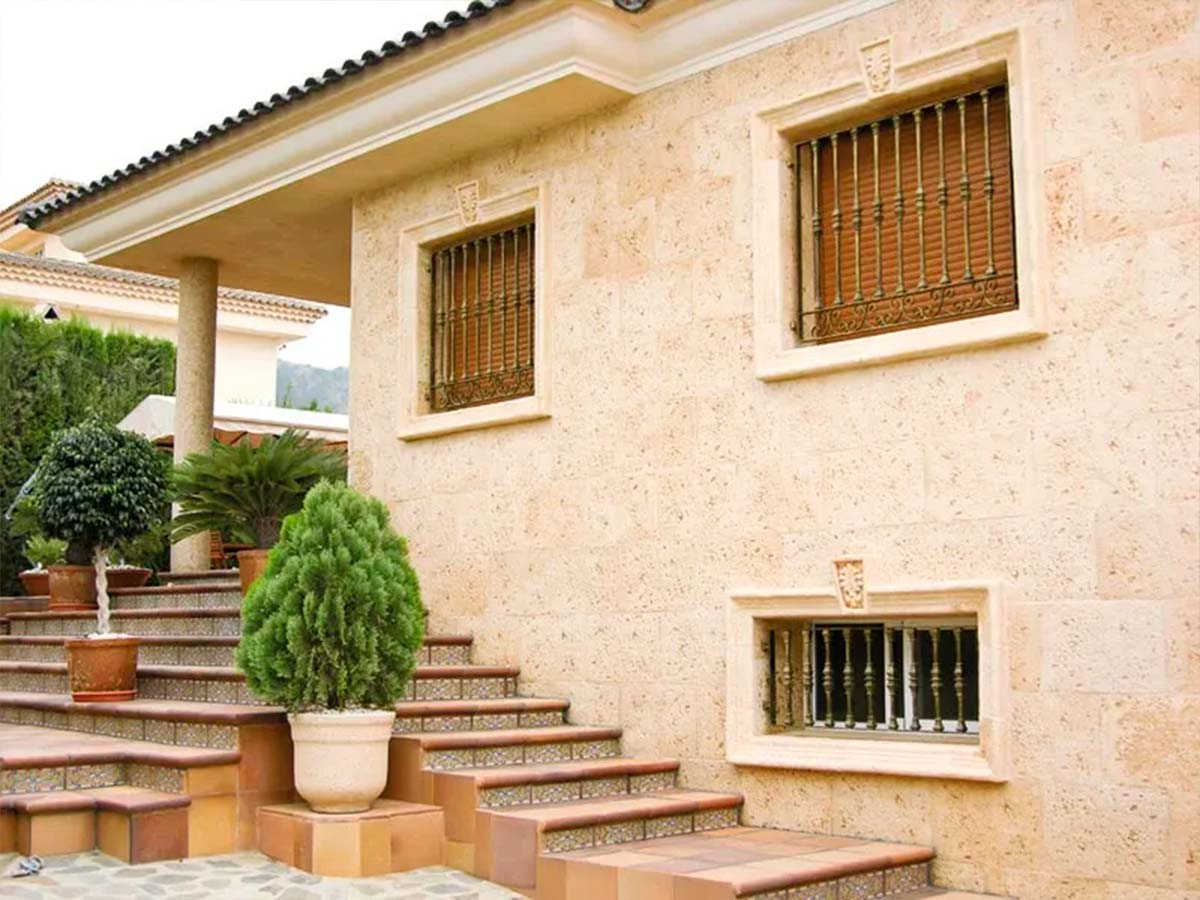 Fachada revestida con acabado de imitación piedra en tonos cálidos