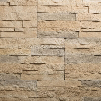 Piezas rectangulares de revestimiento porcelánico con efecto piedra natural en tonos castaño y beige. Superficie con textura rugosa y acabado mate, dispuestas en patrón de hiladas irregulares que imitan la colocación de piedra natural.