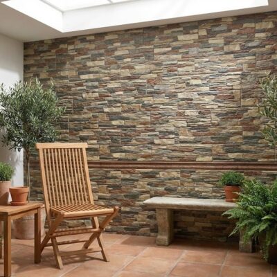 Interior con revestimiento de pared en tonos tierra imitando piedra pizarra natural, mobiliario de madera y plantas en macetas de barro sobre suelo de barro cocido.