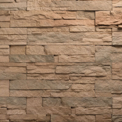 Superficie con textura de piedra natural en tonos beige y marrón cálido, con acabado mate y relieve irregular que imita la mampostería tradicional.