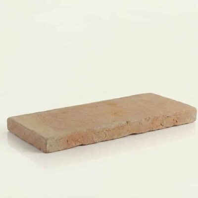 Pieza rectangular de barro cocido artesanal de 15x30 cm con superficie rústica y textura natural. Tonalidad cálida beige-marrón claro, acabado mate con irregularidades características del material cocido.