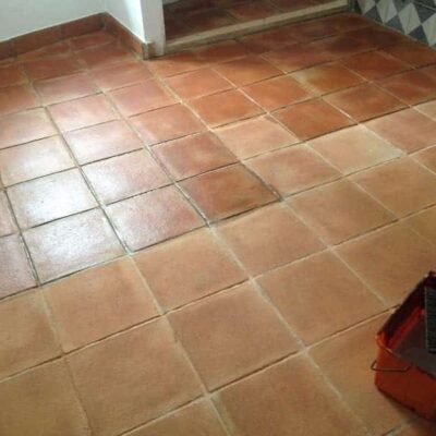Suelo porcelánico con baldosas cuadradas en tonos terracota y beige claro, instalado en espacio interior con acabado mate. Las piezas muestran variación de color natural característica del gres porcelánico imitación madera tradicional.