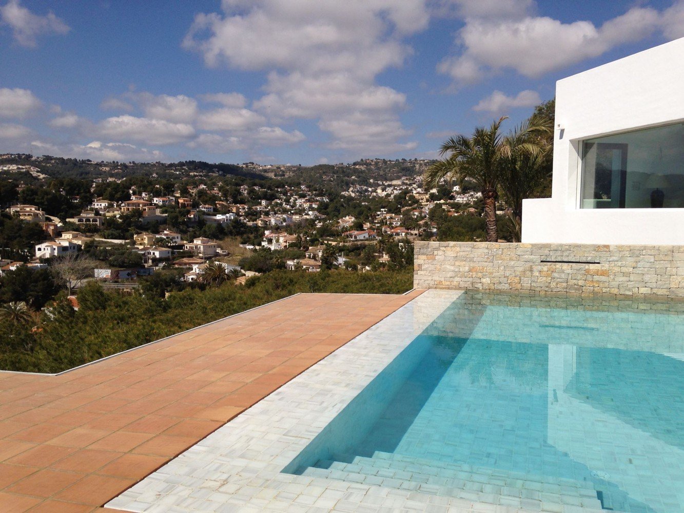 Terraza de una piscina con baldosas de barro cocido en una casa moderna, demostrando su estética y funcionalidad.