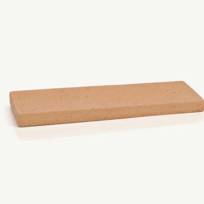Pieza rectangular de zócalo de barro cocido con superficie texturizada y acabado mate en tonos tierra naturales, formato alargado para revestimiento.